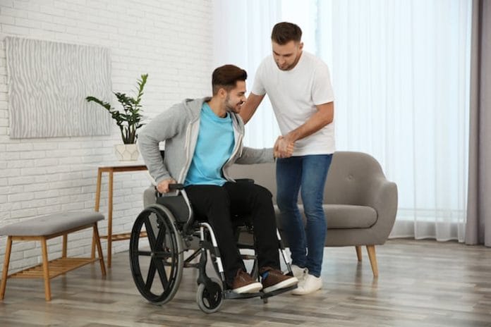 Volunteer helping man in wheelchair at home