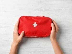 Woman holding first aid kit on wooden background
