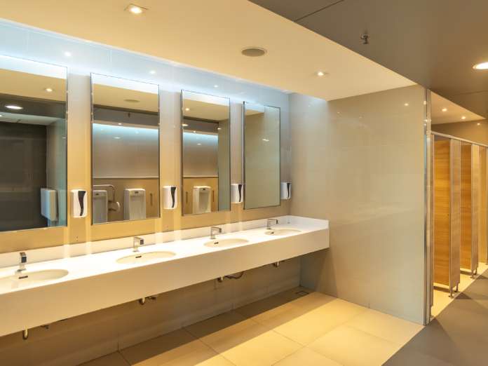 The interior of a well-lit and clean public restroom. The restroom has several stalls, sinks, and mirrors.