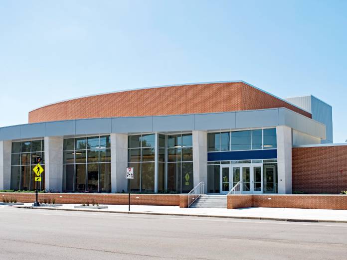 A large brick and metal commercial building contains picturesque windows across the front. A cloudless blue sky is in the back.