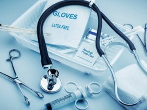A small collection of various medical devices, including a stethoscope, latex-free gloves, a syringe, and prep pads.