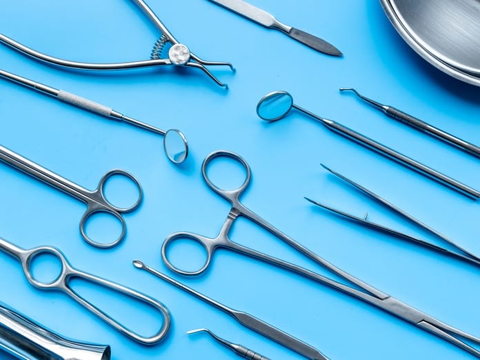 Close-up and top view of a table filled with surgical equipment and metal tools on a blue background.